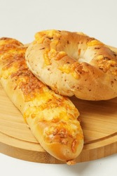 Capturing Savory Delights: An Elongated Cheesy Bread And A Bagel-shaped Treat Adorned With Mozzarella. Presented On A Wooden Tray Against A Pristine White Backdrop.
