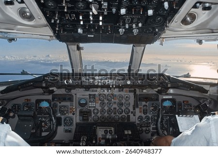 Capturing the scene of pilots navigating an airplane cockpit, soaring above a cloud filled sky during a commercial flight experience