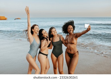 Capturing summer vacation time. Carefree diverse women taking picture together at the beach, female friends having fun and making memories - Powered by Shutterstock