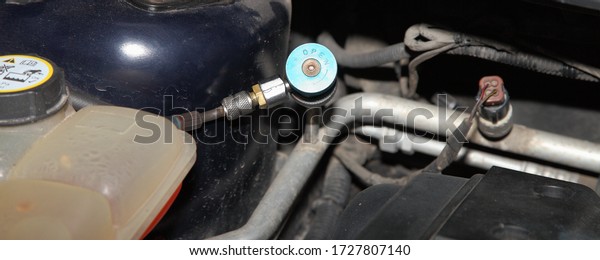 Car A/C blue low pressure valve with pipeline\
and sensor under the hood of the car, vehicle air conditioner test\
work, repair service and\
refilling