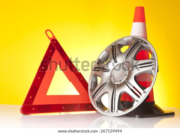 Car accessories - emergency\
road triangle with car hubcap and traffic cone on yellow\
background