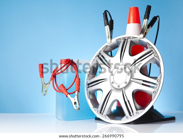 Car accessories - hubcap
with jump start cables and traffic cone and car liquids on blue
background