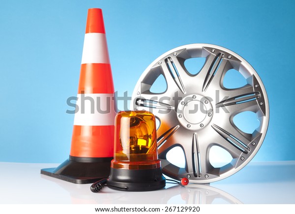 Car\
accessories - car hubcap with traffic cone and emergency vehicle\
amber beacon flashing light on blue\
background