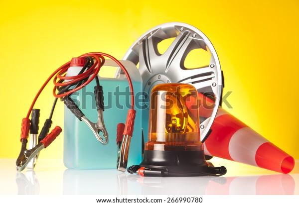 Car accessories - washer fluid with jump start\
cables and emergency vehicle amber beacon light with hubcap on\
yellow background