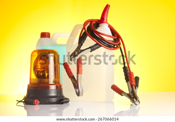 Car\
accessories - washer fluids with jump start cables and emergency\
vehicle amber beacon light on yellow\
background