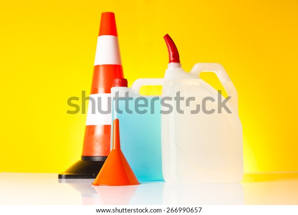 Car accessories - washer fluids with\
orange funnel and traffic cone on yellow\
background