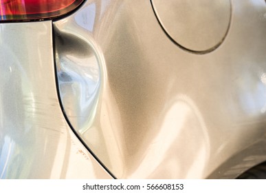 Car accident, body damage, deep dent in the backside of an silver car.