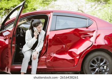 Accidente automovilístico, protección del seguro de automóviles, colisión de Reclamo, emergencia automática. Una mujer está sentada en un auto rojo con la parte delantera destrozada. Ella está hablando por su teléfono celular.
