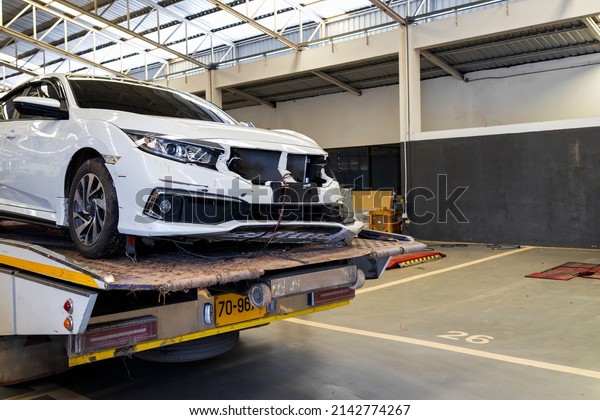 car\
accident crash on car trailer in automobile repair service center\
with soft-focus and over light in the\
background