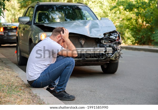 Car\
accident. Man holding his head after car accident. Man regrets\
damage caused during car wreck. Man driver is indignant had an\
accident on road. Headache injury blow to\
head.