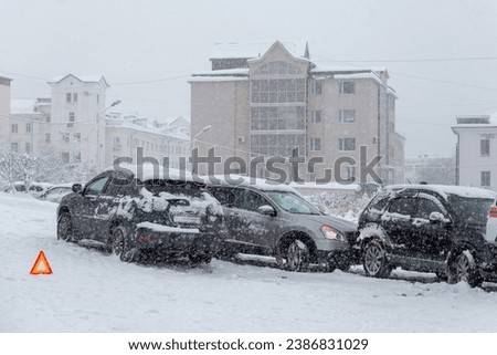 Car accident on a city street. Several cars crashed on a slippery snow-covered road. Difficult road conditions during snowfall. Snowy winter weather.