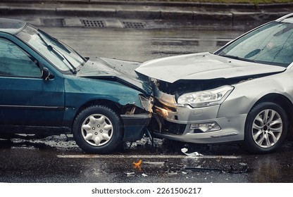 Car accident on wet road during rain, head on collision side view. Two cars damaged after head-on collision, car crash. Car crash on the street, damaged cars after collision. Traffic rules violation - Shutterstock ID 2261506217