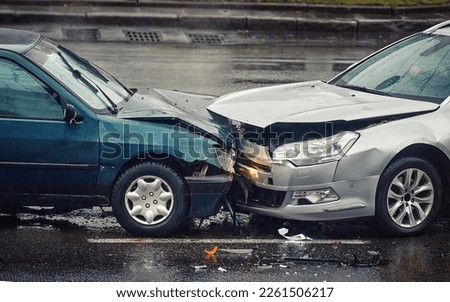 Car accident on wet road during rain, head on collision side view. Two cars damaged after head-on collision, car crash. Car crash on the street, damaged cars after collision. Traffic rules violation