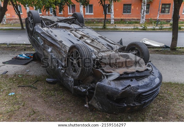 Car accident.\
An overturned car lying upside down on the street after an\
accident. Car lands on roof after losing control and crashes into\
tree. NIPRO, UKRAINE - May 19,\
2022.