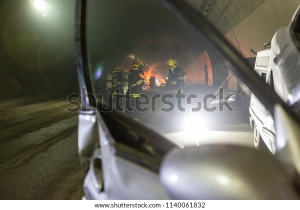 Car accident scene inside a tunnel, firefighters\
rescuing people from cars