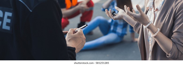 Car Accident Witness Giving Statement To A Policeman, Victim In The Background, Panorama