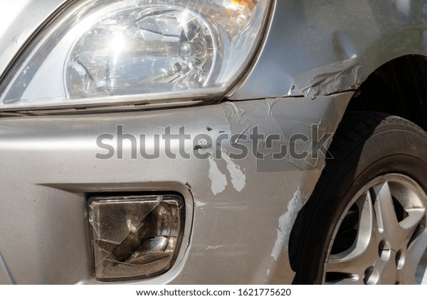 Car after crash accident on street, damaged front\
bumper. Adhesive tape used.