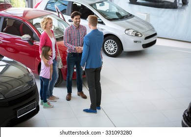car agent handshake with his daddy and congratulate the family on buying car 