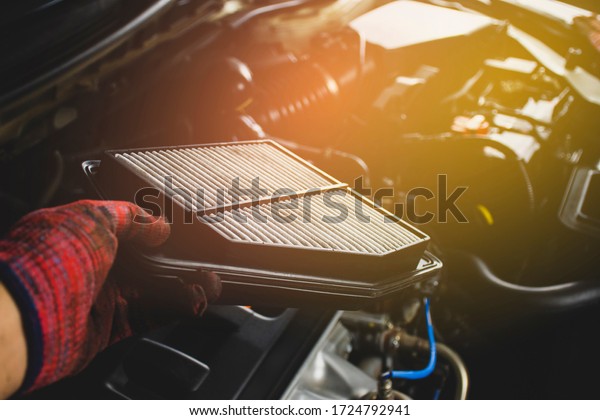 Car air\
filter in a hand of mechanic man is installing into air filter\
socket of car engine,Automotive part\
concept.
