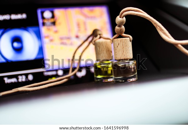 Car air perfume freshener bottles inside the car\
with part of car dashboard. Little glass bottles with wooden lid\
and aromatic liquid.