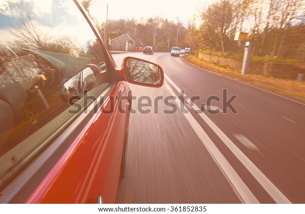 A car approaching a road safety, speed\
camera. The image has added grain and\
styling.
