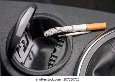 Car Ashtray With A Smoldering Cigarette And Burned Match