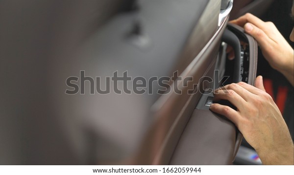 Car assembly. The worker takes the car. Horizontal\
view of a man cleaning a car. Worker repairing a handle at the car\
door