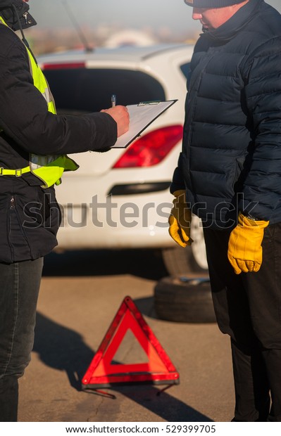 Car assistance technician checking auto and\
writing on clipboard. Car breakdown. Red emergency sign, spare\
wheel and wrench.