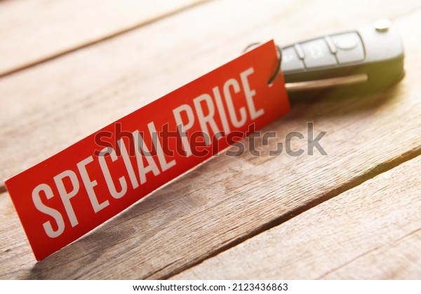 Car auction concept. Special price!\
Vehicle security key with tag on the wooden\
background