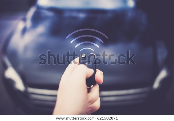 Car Auto Alarm and Remote Central\
Lock. Car Keys in Driver Hand Sending Signal to the\
Vehicle.