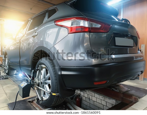Car in auto\
service. Sensors on SUV wheels check alignment camber toe. Work\
with chassis and suspension of\
car