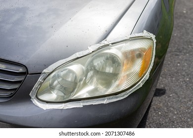 Car Auto Vehicle Front Foggy Dirty Headlight With Protective Tape Around Light Taped To Protect Paint For Cleaning Polishing At Home Driveway Of House Outside