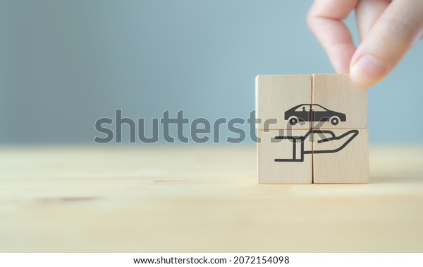 Car (automobile) insurance and collision damage\
waiver concepts. Hand holds the wooden cubes with care protection\
symbol on  grey background and copy space. Car insurance and\
business banner.