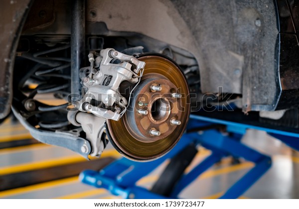 car automobile mechanic working on repairing\
the brake drum and disc vehicle, car in for service workshop for\
male car mechanic fixing problems replacing broken parts of using\
tools and equipment