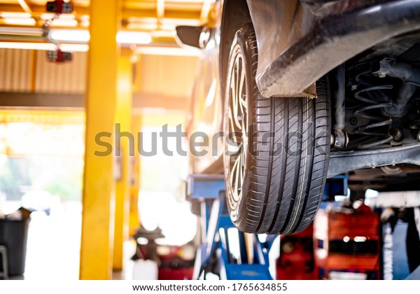 car automobile mechanic working on repairing\
the wheel tire of vehicle, taking car in for service workshop for\
male car mechanic fixing problems replacing broken parts of using\
tools and equipment
