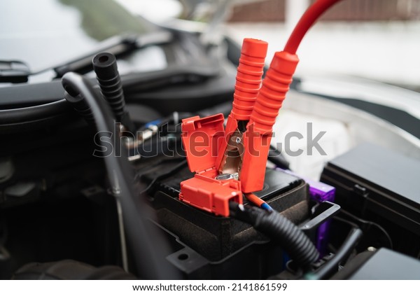 Car battery jump cable is dead. car battery\
charger The car battery is exhausted. Service jumper battery\
transportation concept.