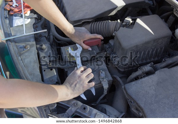 Car battery repair under the hood, female hands\
car repair