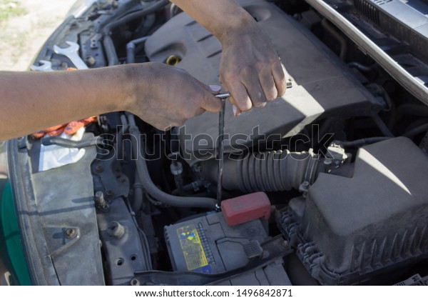 Car battery repair under the hood, female hands\
car repair