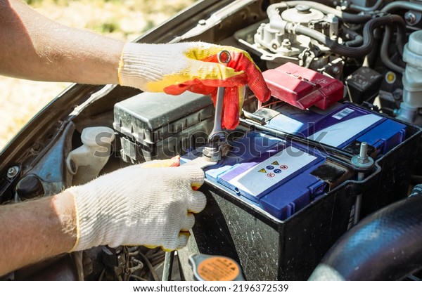 Car battery replacement. The car mechanic\
repairs the car, unscrews the battery\
mount.