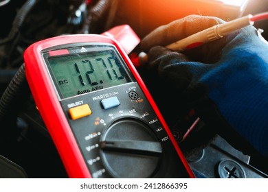 Car battery voltage testing with a digital multimeter by auto technician, Car voltage current display on black screen of digital multimeter, Car maintenance service concept