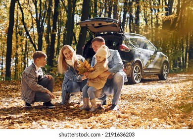 Car is behind. Happy family is in the park at autumn time together. - Shutterstock ID 2191636203