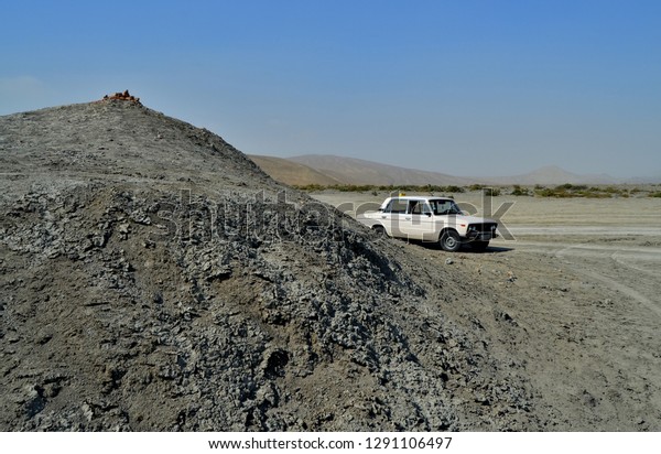A car behind a mud\
volcano on the desert