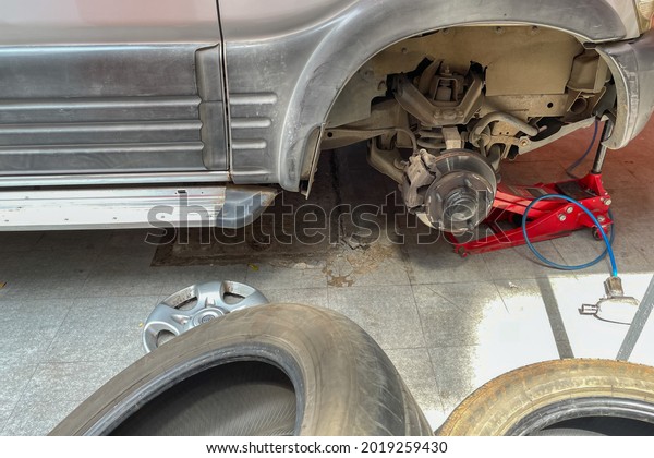 A\
car being lifted with a hydraulic jack under it and the tyres being\
replaced in a motor garage at Pune India on 7 July\
2021