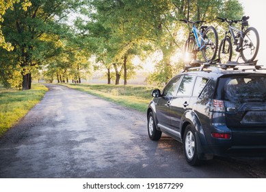 Car With Bicycles In The Forest Road At Sunset