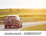 Car with bikes on rear rack driving on rural