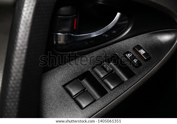 Сlose-up of the car  black interior:  the side door\
buttons: window adjustment buttons, door lock and other buttons.\
