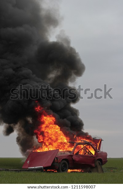 car blast burning \
red car burns on green lawn\
black smoke