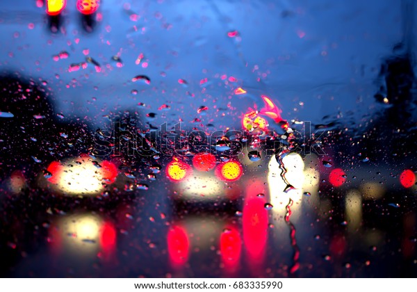 In the car, blur image\
of rain on the road as night background,night storm raining car\
driving concept.