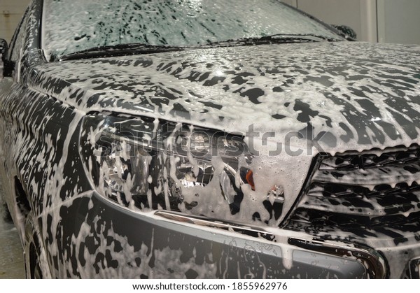 The car body is covered with soap suds to remove\
dirt. Car wash