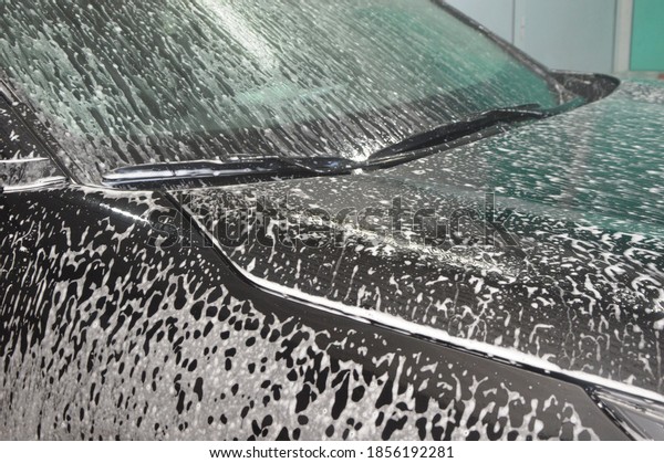 The car body is covered with soap suds to remove\
dirt. Car wash